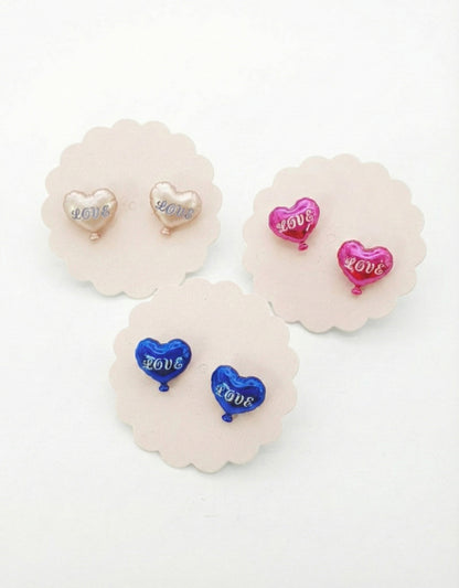 Flat lay of three heart balloon earring pairs on white scalloped pads