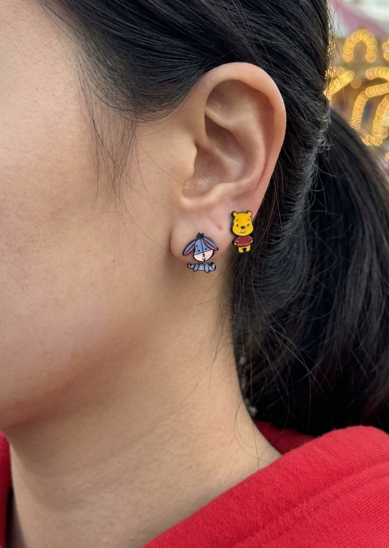 Woman wearing cute mismatched Winnie the Pooh and Eeyore silver post earrings outdoors