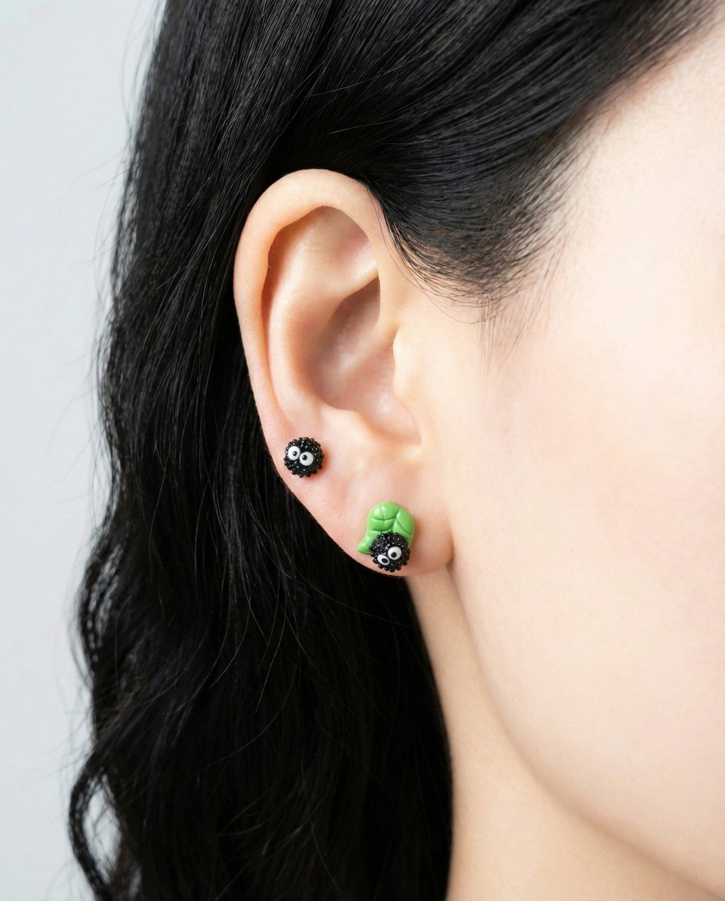 Side view of model ear wearing layered green leaf Soot Sprite earrings showing 3D sculptural detail