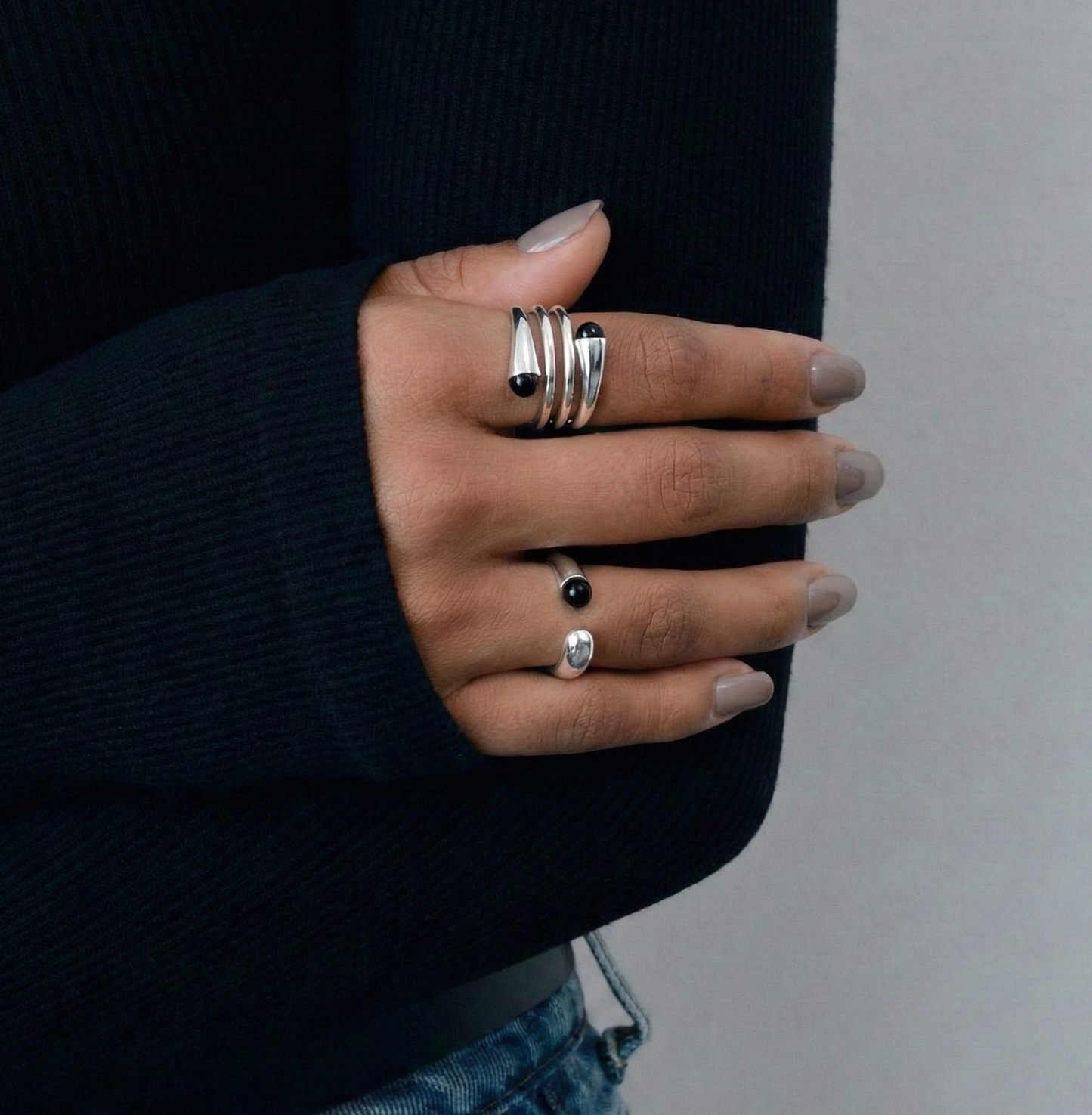  Model in navy knit wearing 925 sterling silver dual black onyx rings on index and ring finger — stacked look