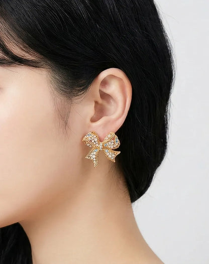 Pair of Gold Pink crystal bow stud earrings with opal and rhinestone detail on illustrated jewelry card — close-up product shot, handmade in Korea
