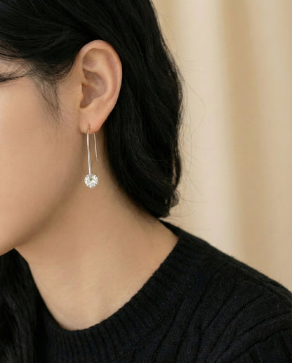 Side view of woman wearing silver cubic zirconia long drop earrings with black outfit