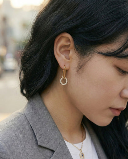 Outdoor shot of woman wearing gold oval link drop earrings, professional style