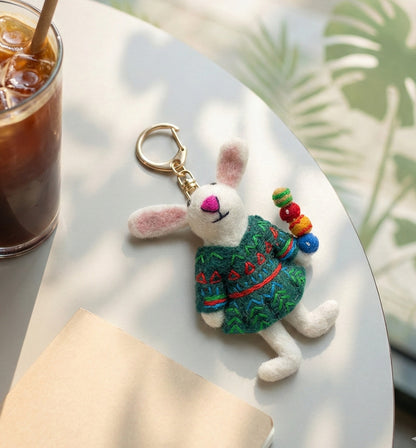Flat lay of wool felt rabbit bag charm with candied fruit next to iced coffee on cafe table