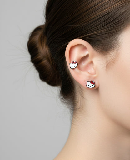 Hello Kitty enamel stud earrings stacked on ear, cute red-bow character styling, silver post finish