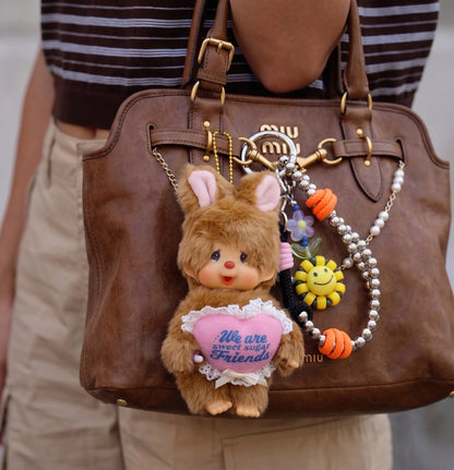 Downtown girl bag charm 8ttitto8 silver smiley flower bead strap keychain with Monchhichi on Miu Miu vintage bag, outdoor candid.
