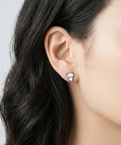 Close-up ear shot of single Shiro white dog enamel stud earring on model's earlobe