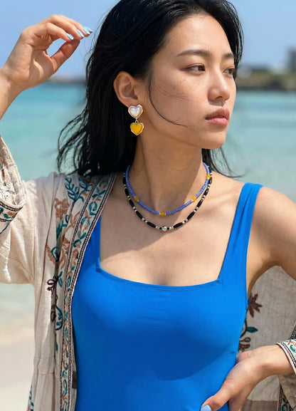 Yellow heart drop earrings with blue swimsuit and layered beaded necklaces, K-style resort jewelry.