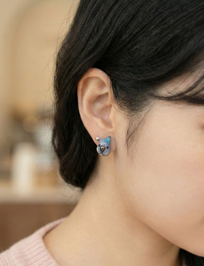 Model wearing blue parrot stud earring layered with silver ball stud, earscape styling 