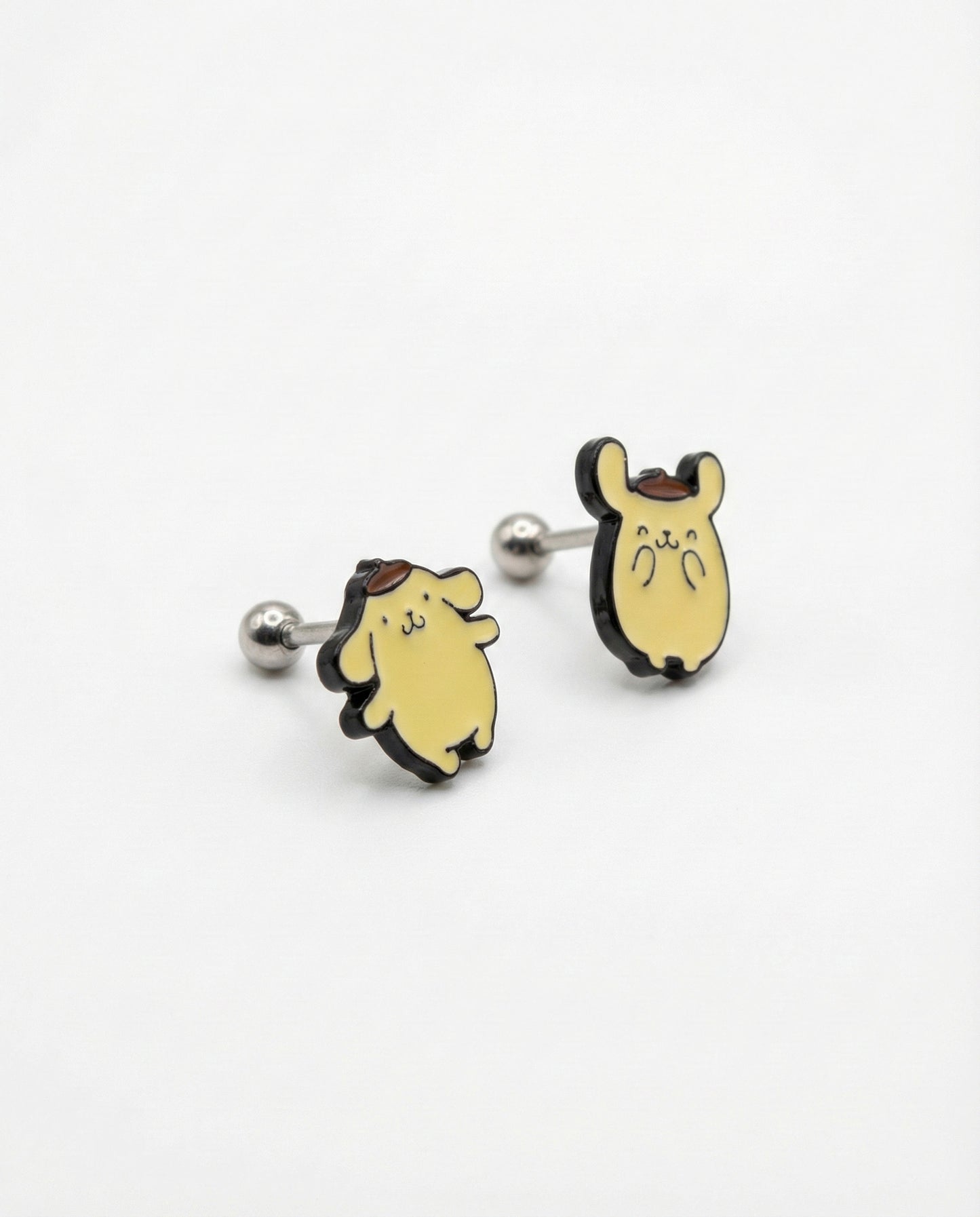 Flat lay of two Pompompurin titanium post piercings showing classic standing and hands up poses