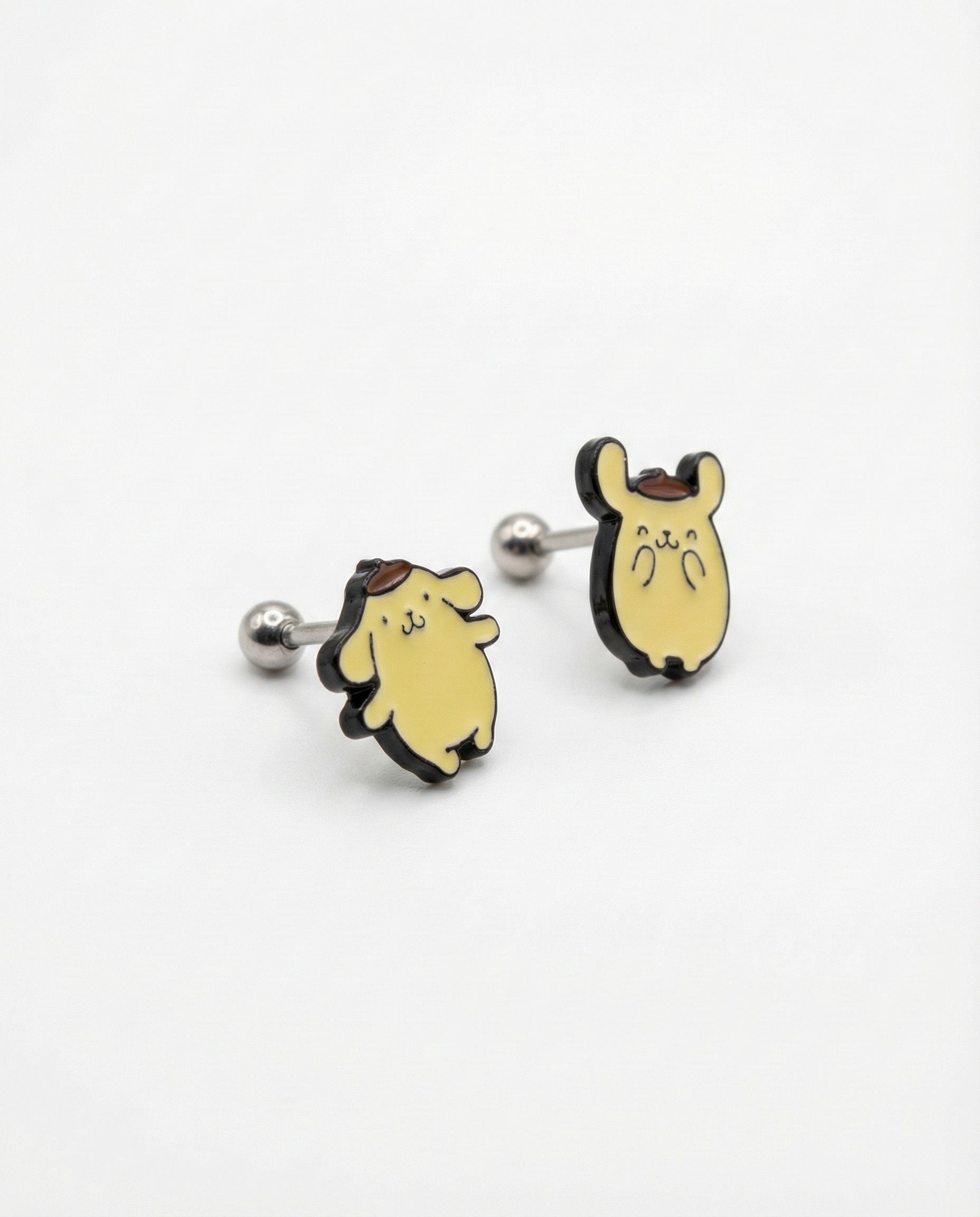 Flat lay of two Pompompurin titanium post piercings showing classic standing and hands up poses
