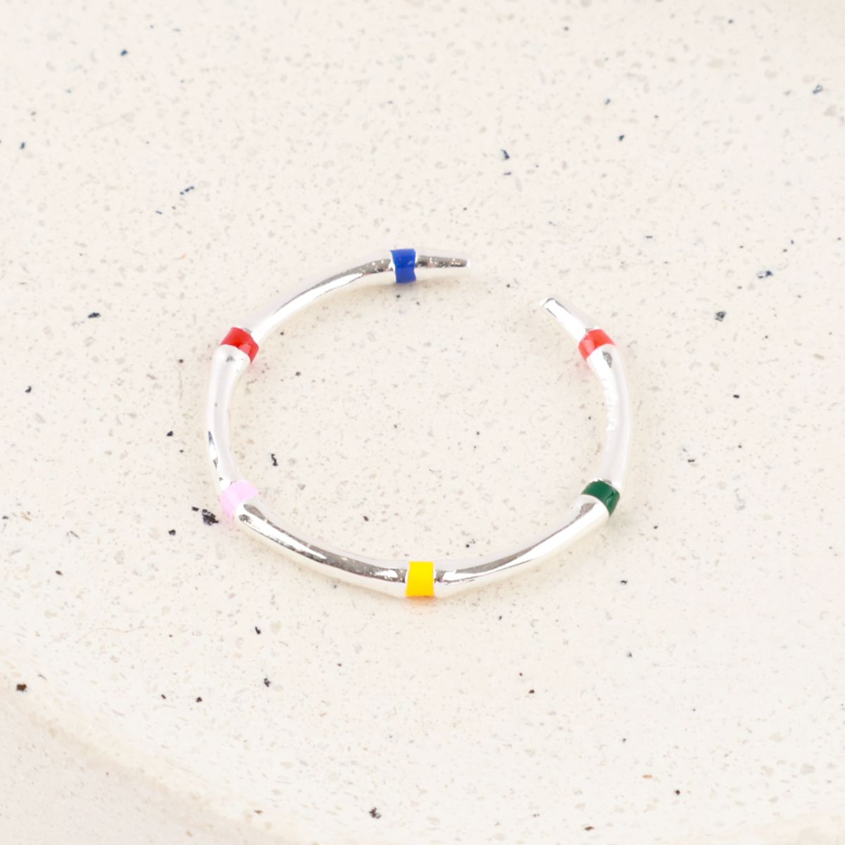 Top view of single 925 silver five-color enamel open ring on terrazzo surface showing C-band adjustable structure