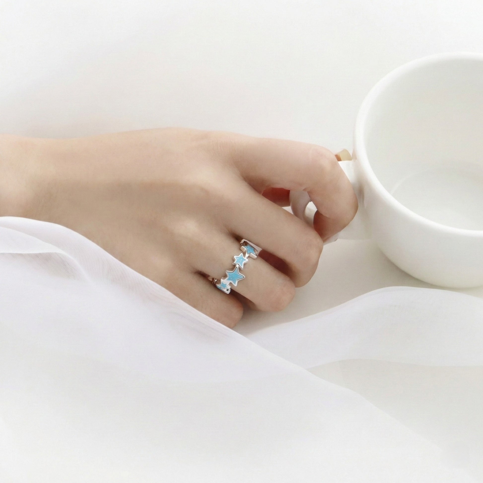 Hand wearing sky blue star ring with white cup showing everyday styling