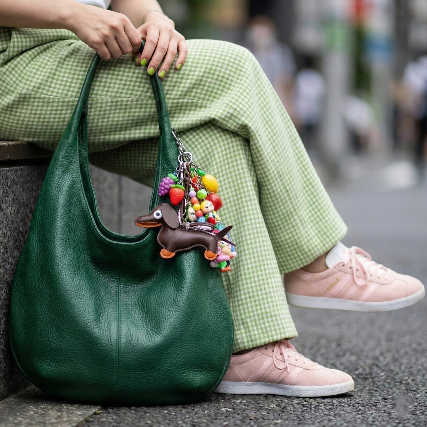 Brown leather Dachshund purse charm with colorful fruit charms and beaded decorations on green handbag