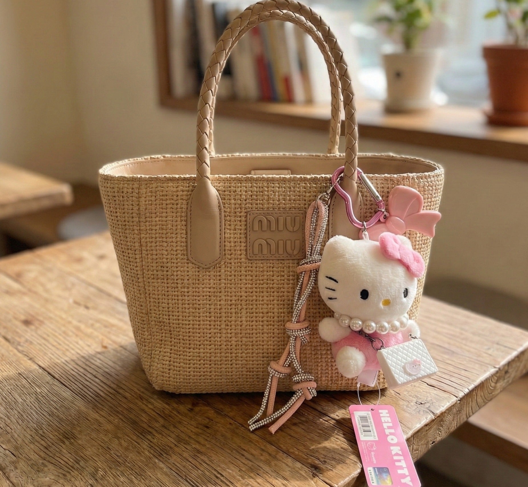 Hello Kitty plush keychain with quilted mini bag and crystal rope strap displayed on marble cafe table — coquette aesthetic accessory