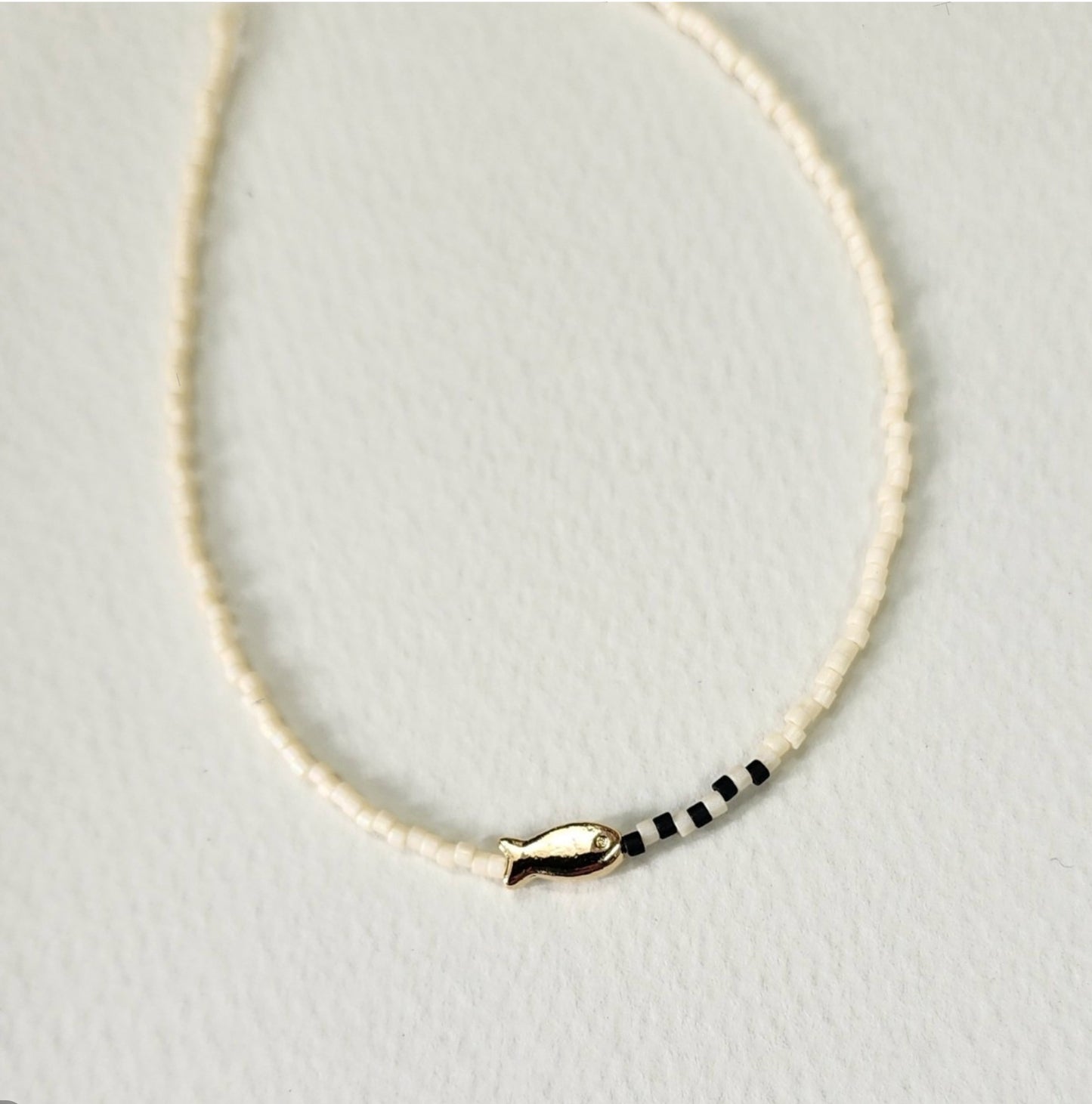 Pure ivory seed bead necklace with gold fish charm and black accent beads minimalist design
