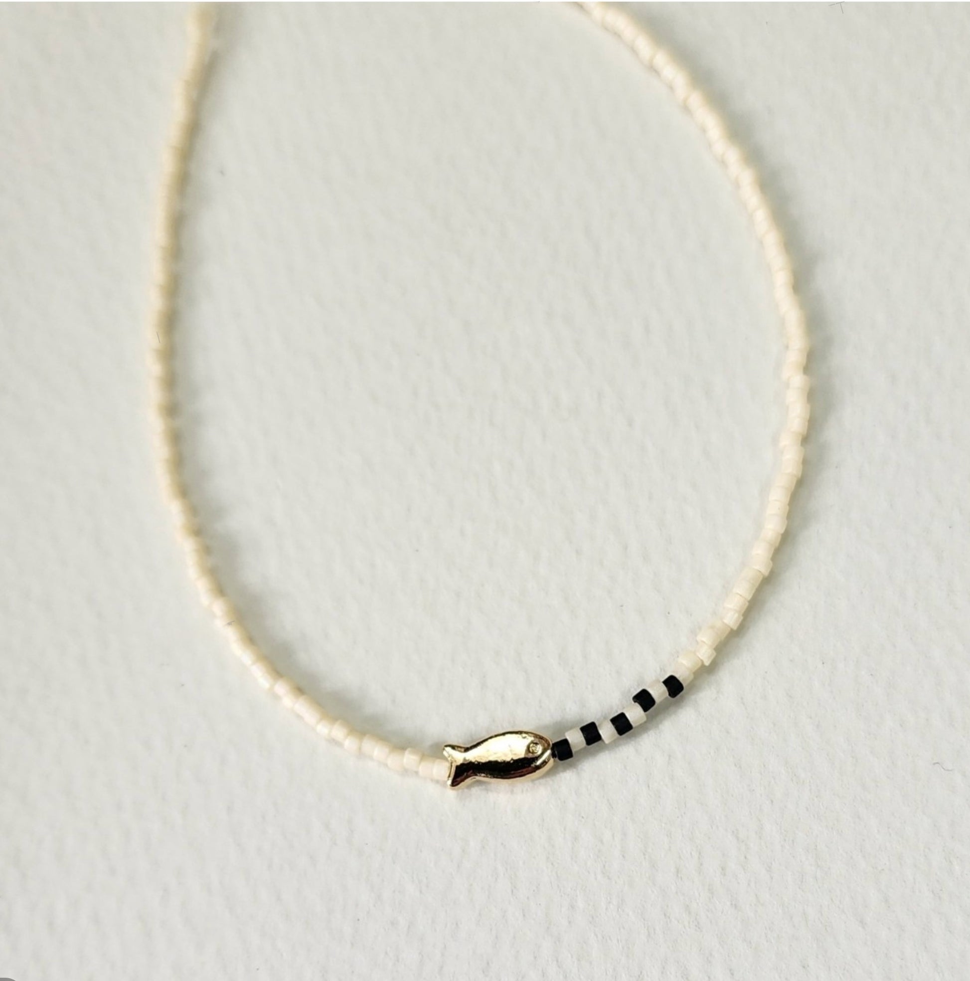 Pure ivory seed bead necklace with gold fish charm and black accent beads minimalist design