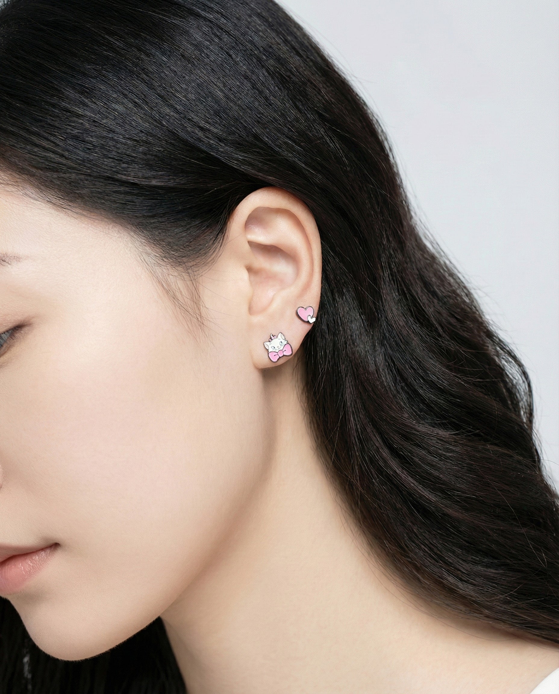 Woman wearing white cat and heart mismatched earrings - cute character stud earrings