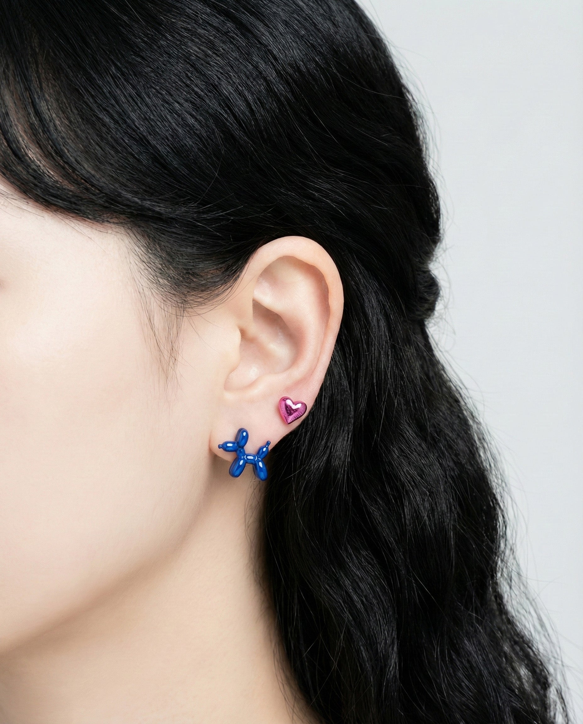 Model wearing rose gold balloon dog earring with love heart charm showing layered ear styling
