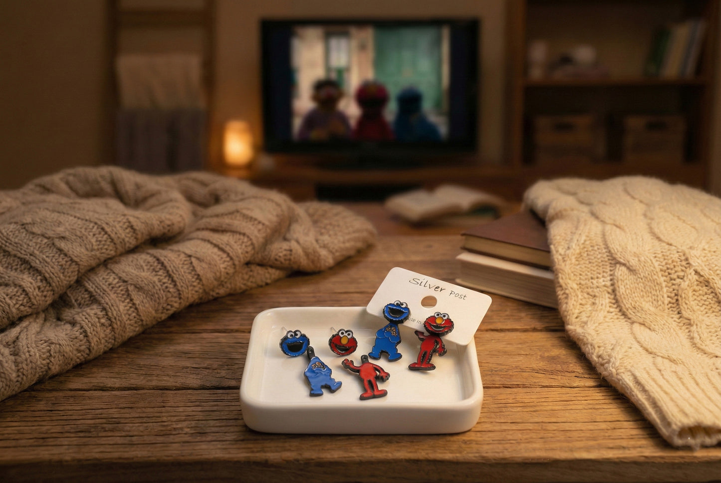 Full Sesame Street earring set displayed on cozy wood tray; Elmo and Cookie Monster in both face and body variants, styled for a holiday gift scene.