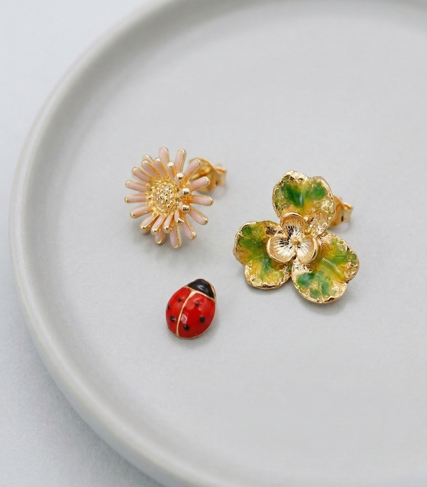 Retro Red floral and ladybug 3-piece earring set elegantly displayed on a light grey ceramic plate.