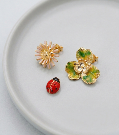 Retro Red floral and ladybug 3-piece earring set elegantly displayed on a light grey ceramic plate.