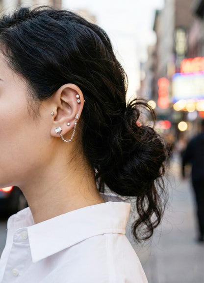 Updo hairstyle showing full ear stack with connected chain piercing jewelry