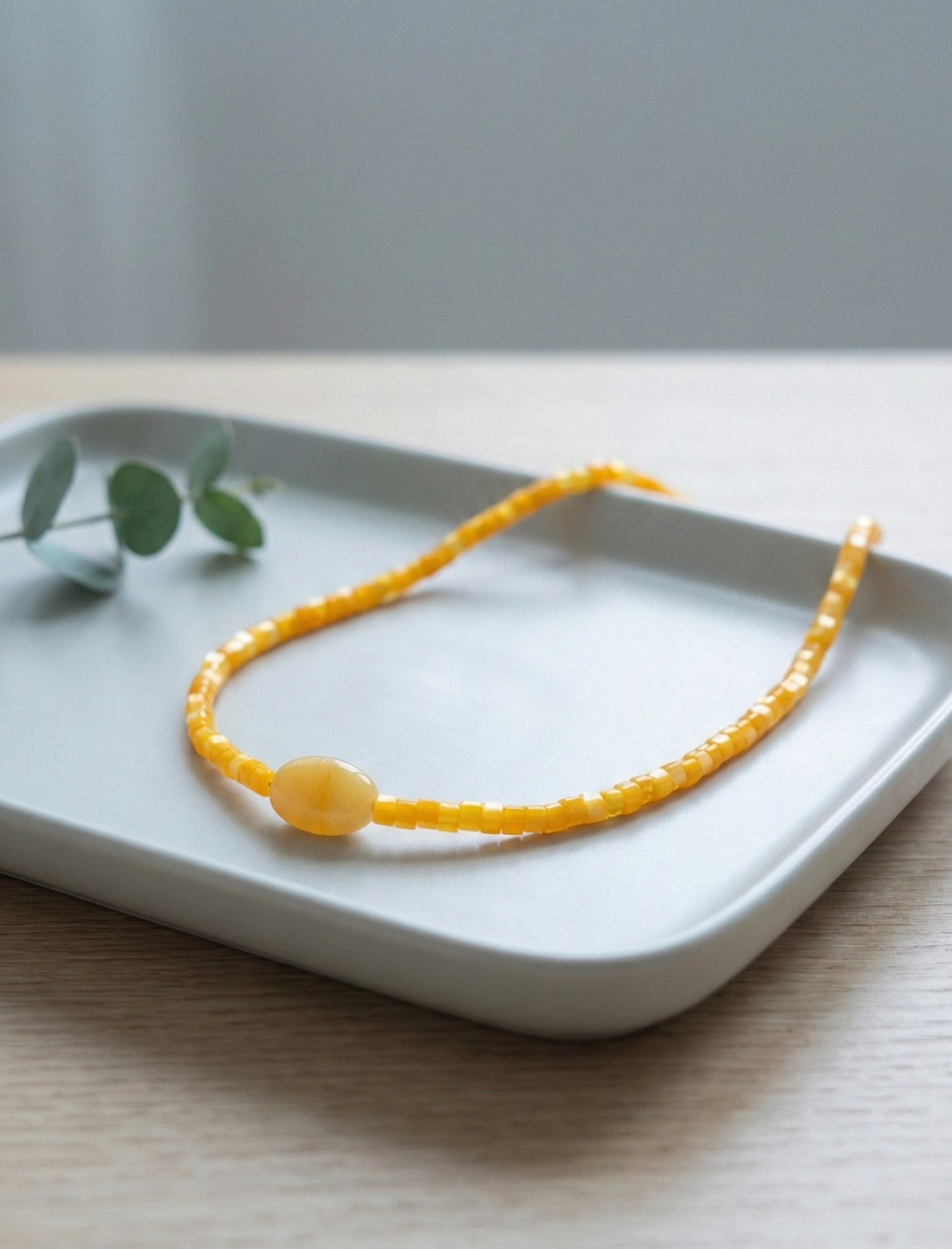 Yellow jade gemstone choker with matching shell heishi beads on ceramic plate