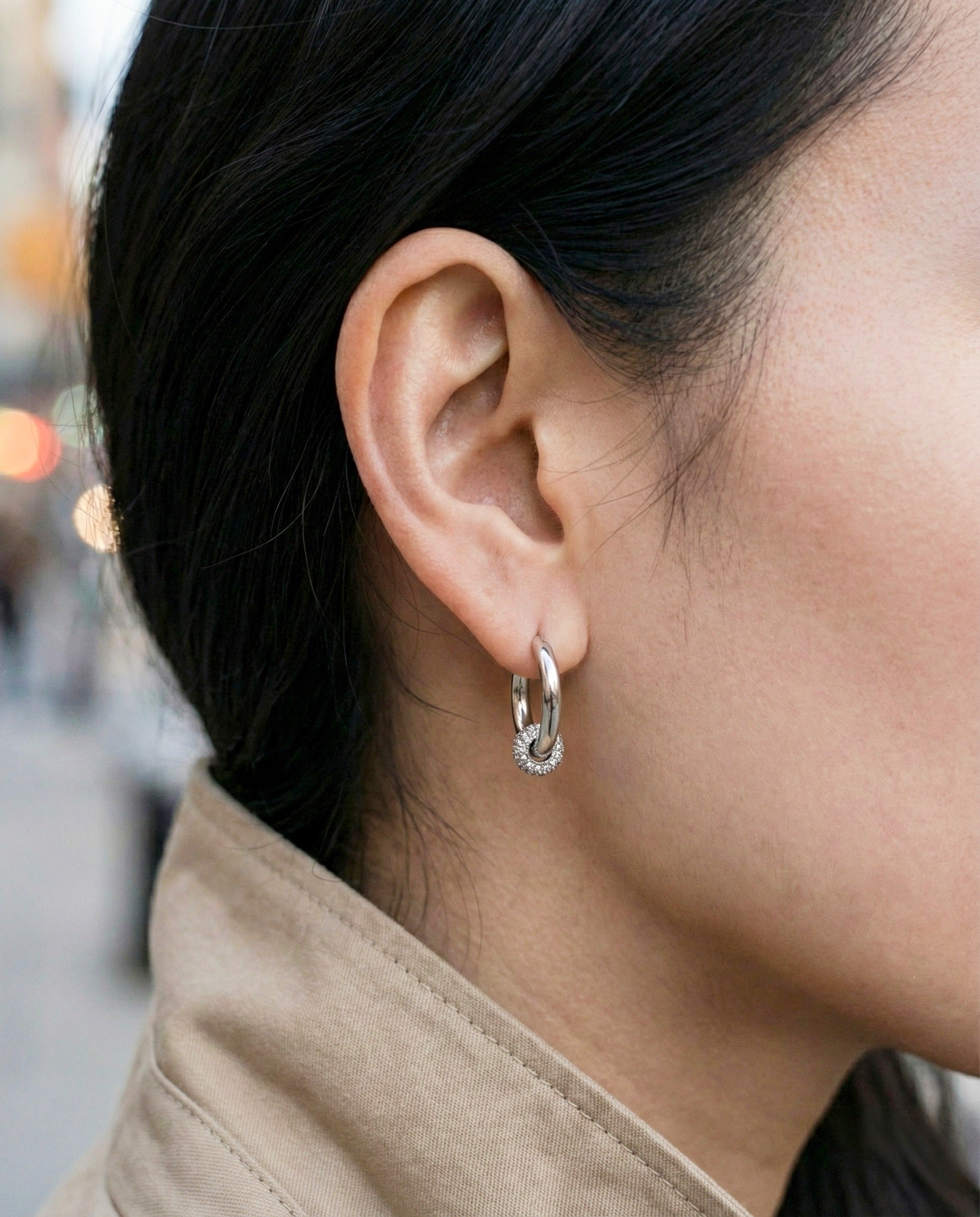 Woman wearing silver pave huggie earrings with cartilage piercing layered look