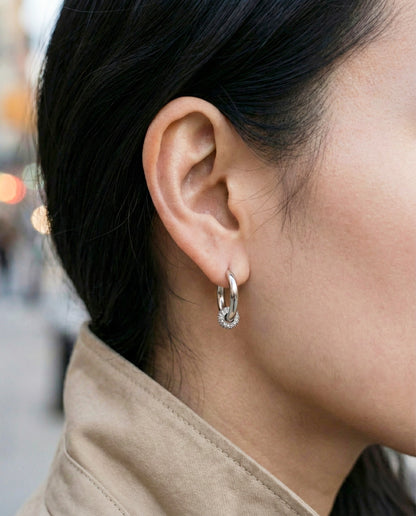 Woman wearing silver pave huggie earrings with cartilage piercing layered look