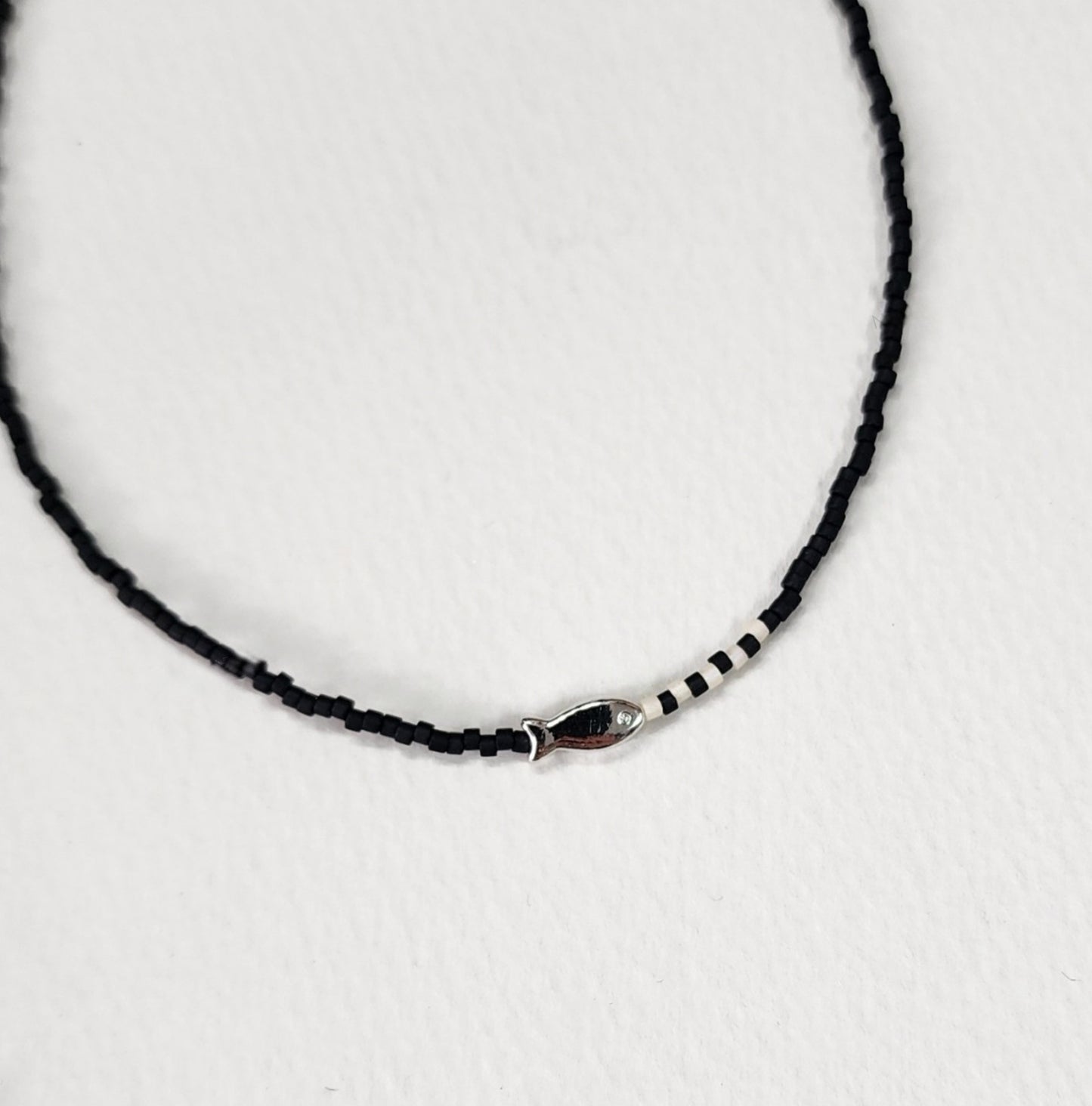 Deep black seed bead choker with silver fish pendant and white accent beads elegant style