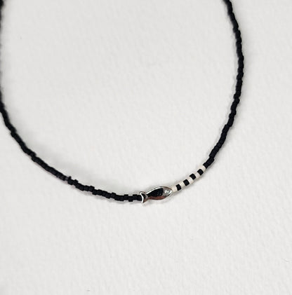 Deep black seed bead choker with silver fish pendant and white accent beads elegant style
