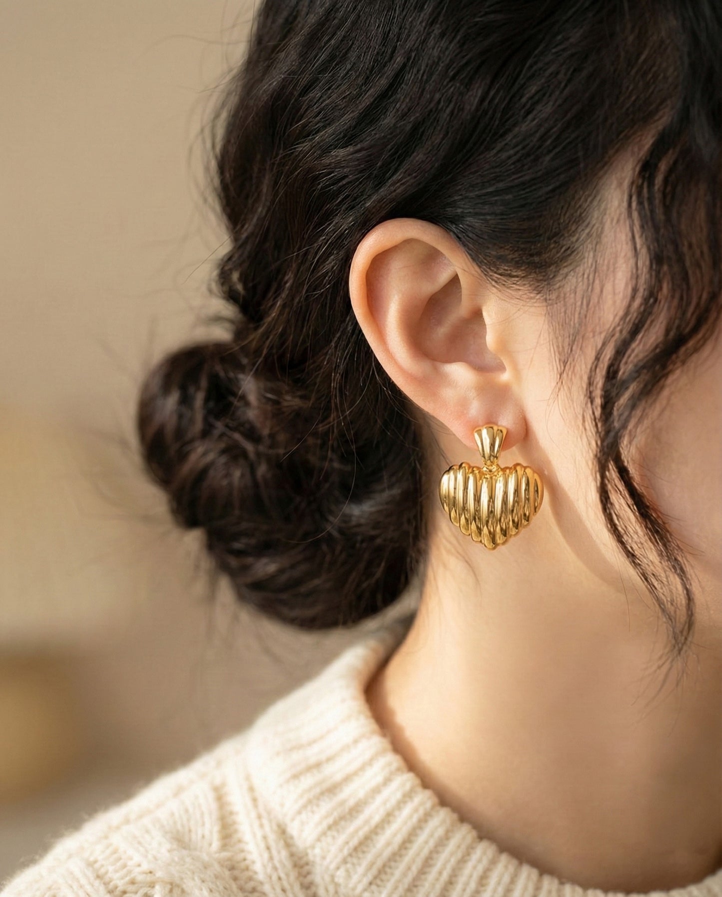 Model wearing gold vintage heart earrings with beige knit outfit
