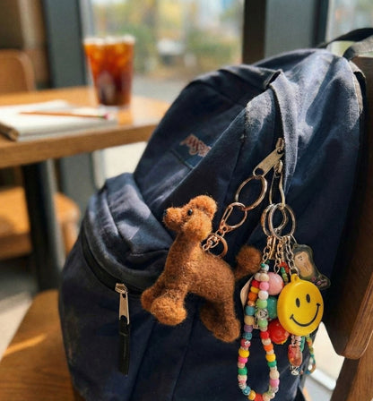 Brown wool poodle keychain on navy blue backpack with colorful beaded keychains and smiley face charm
