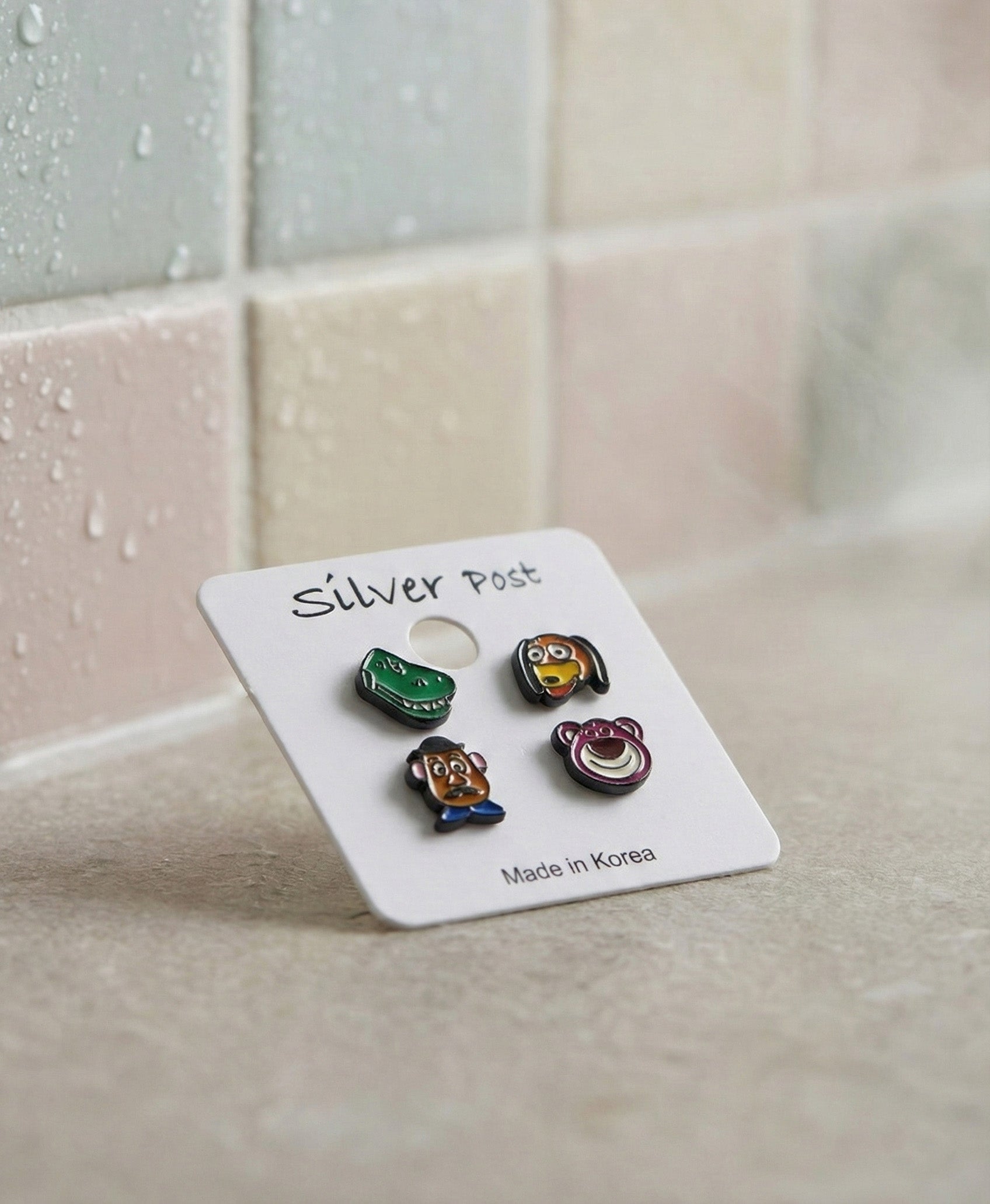 Korean made Toy Story earrings Type B set on white card against bathroom tile
