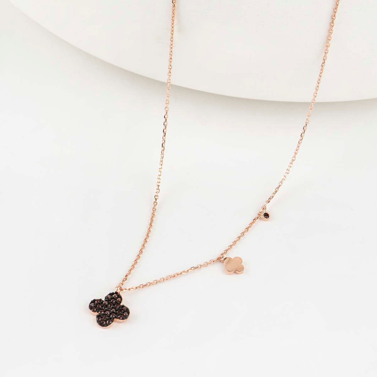 925 sterling silver cognac brown pavé clover necklace with asymmetric rose gold mini charm and black cubic – flat lay on white background