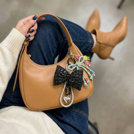 Black puffy bow bag charm with mint beaded strap on tan shoulder bag casual outfit