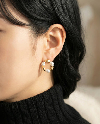 Gold baroque freshwater pearl wreath earrings styled with black knitwear - close-up ear shot showing pearl details