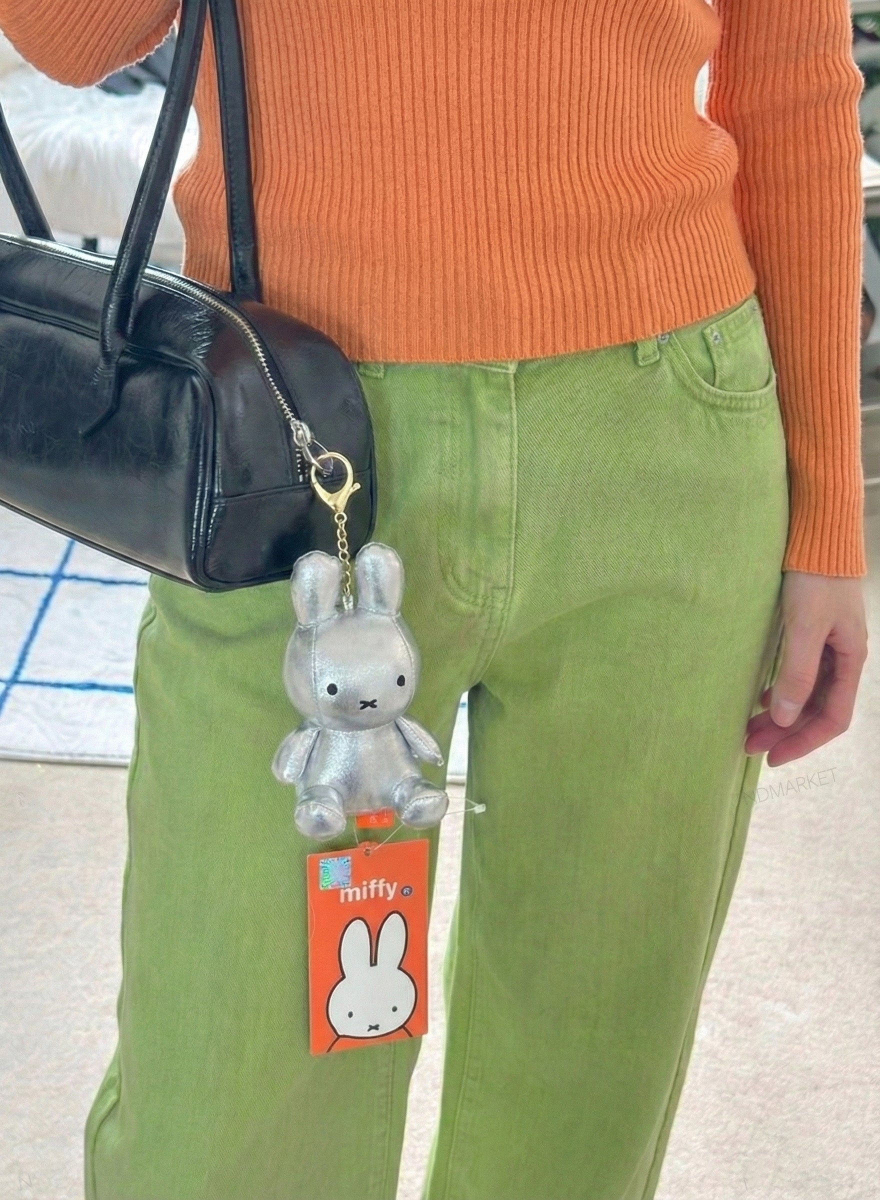 Woman wearing silver metallic Nijntje Miffy keychain on crossbody bag - Korean fashion trend