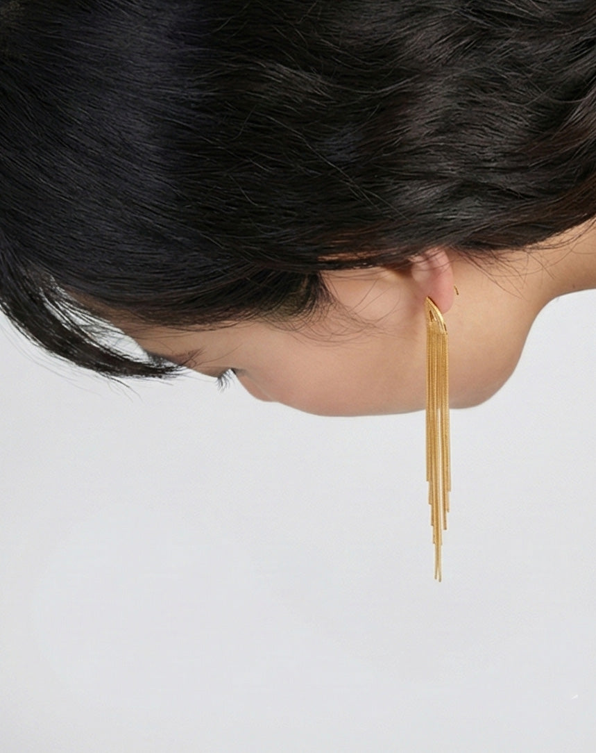 Gold tassel fringe earrings shown in motion as woman looks down, flowing chain detail