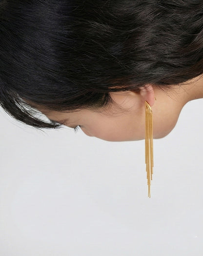 Gold tassel fringe earrings shown in motion as woman looks down, flowing chain detail
