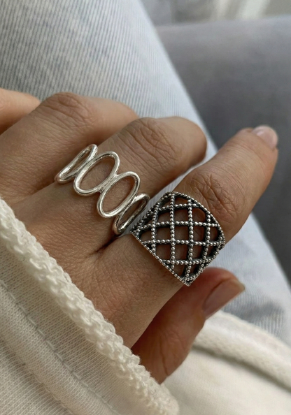 Oval loop ring and lace lattice ring worn on hand, white lace-trim fabric background, showing both 925 sterling silver statement rings together