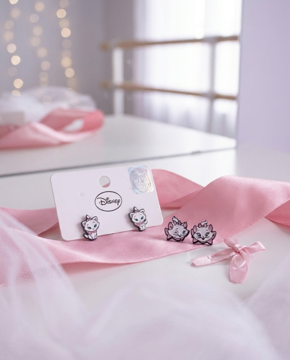 Lifestyle flat lay of Disney Marie earrings with pink ribbon and vanity mirror