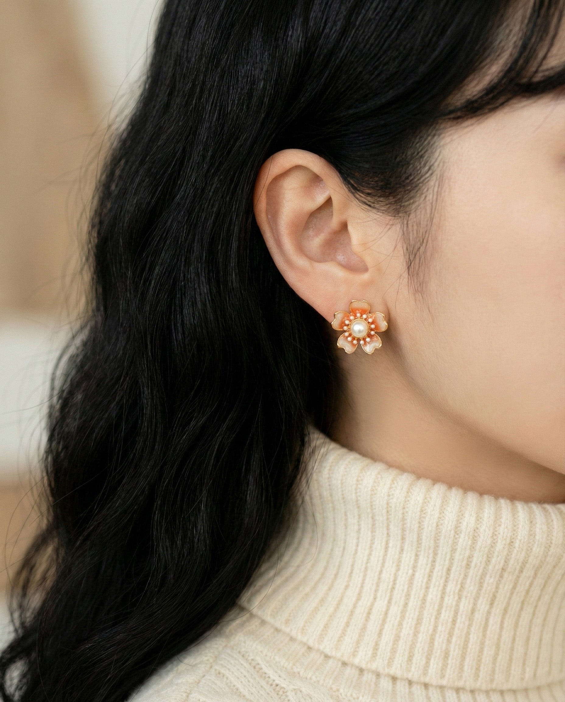  Close-up lifestyle shot of coral peach bloom earrings worn with cream knit sweater, Asian model