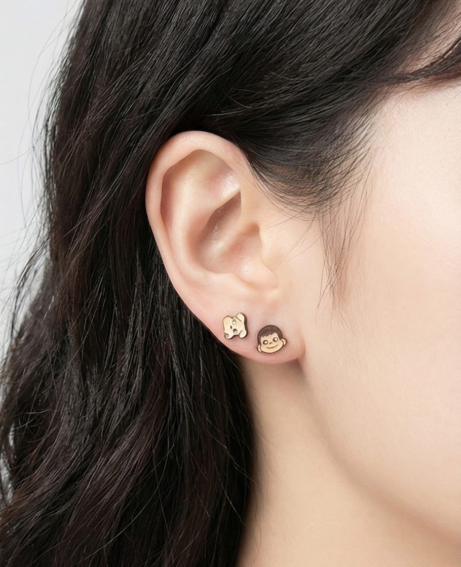 Close-up of ear wearing yellow puppy and brown Poko character stud earrings demonstrating small size and cute kawaii design