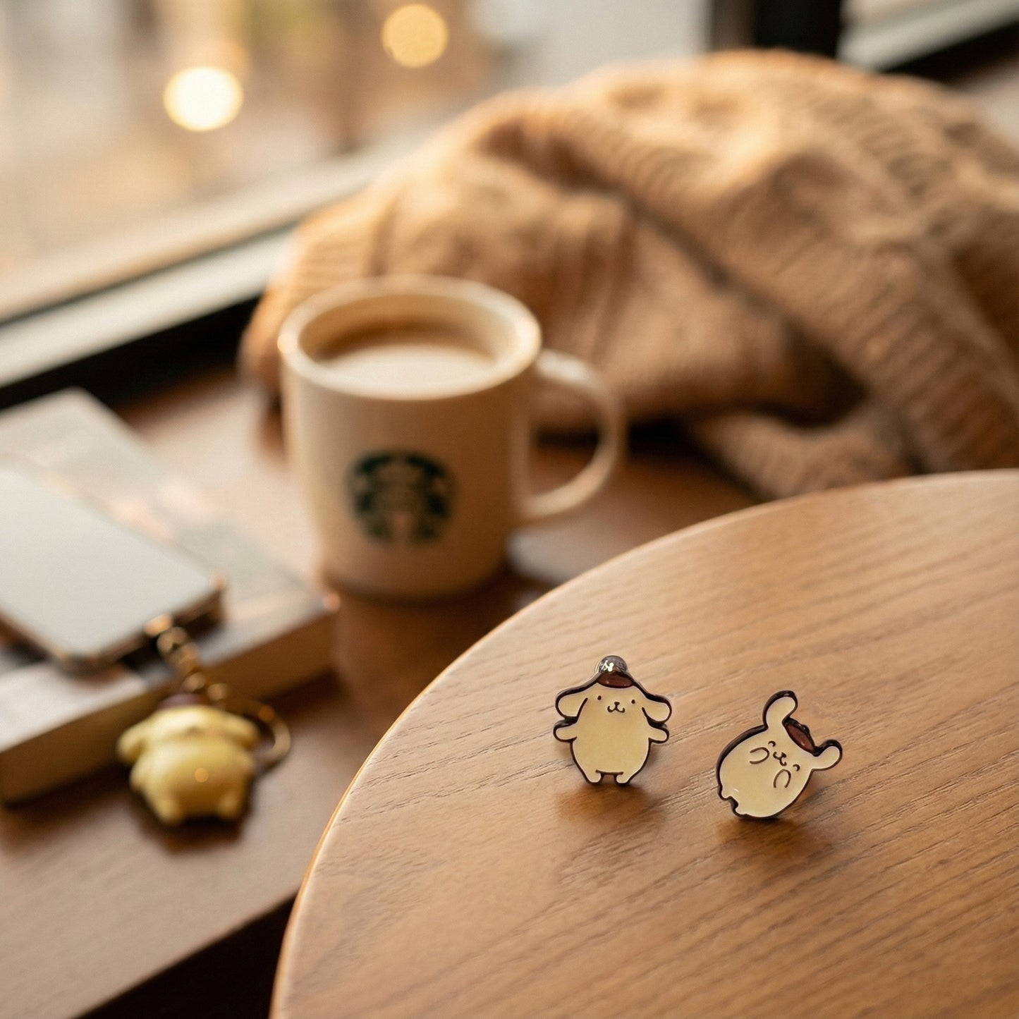 Lifestyle shot of Pompompurin piercings on wooden tray with coffee and cozy aesthetic