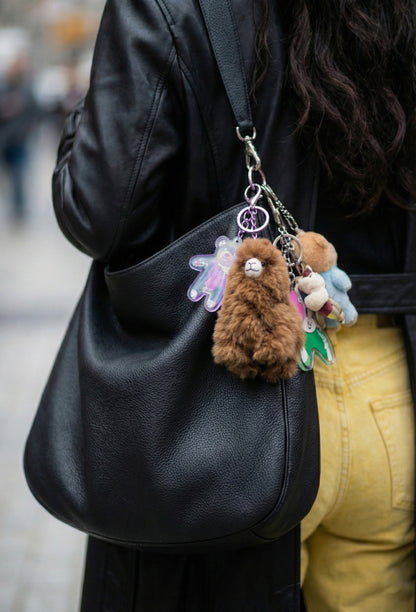 Alpaca plush keychain on black leather backpack with colorful charms street style