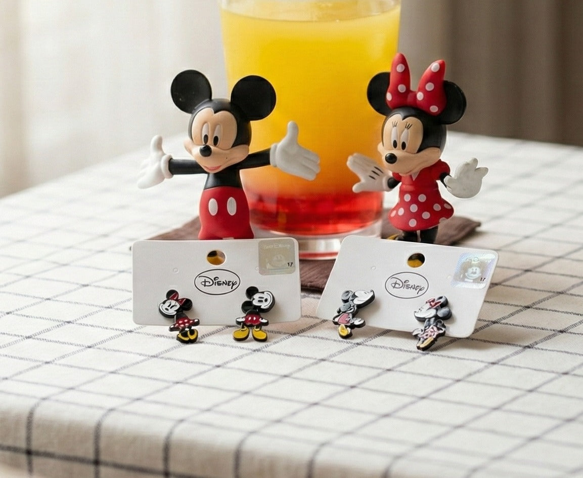 Flat lay of Disney Mickey and Minnie front-back earrings in packaging with character figurines and colorful drink