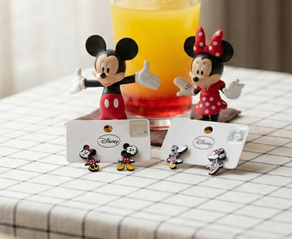 Flat lay of Disney Mickey and Minnie front-back earrings in packaging with character figurines and colorful drink