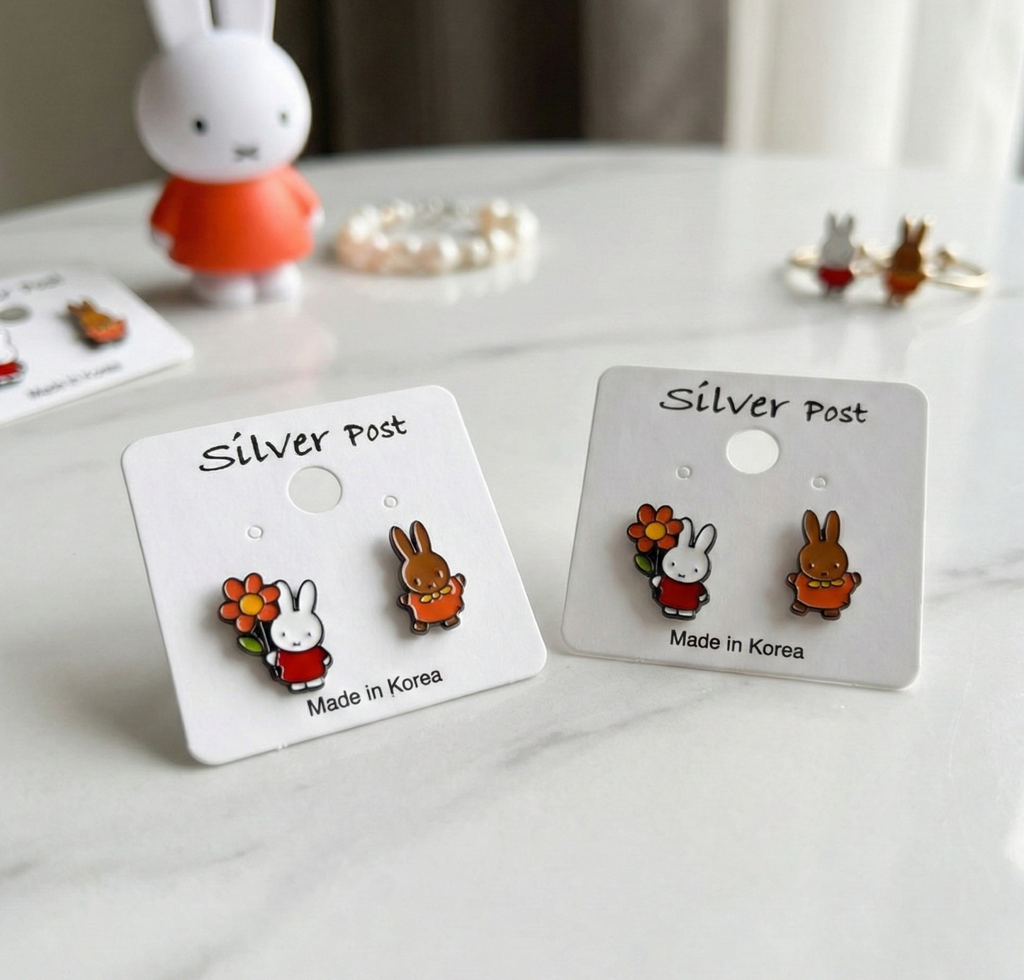 Two pairs of Miffy Melanie earrings on white cards showing Made in Korea silver post marking, friendship gift set idea